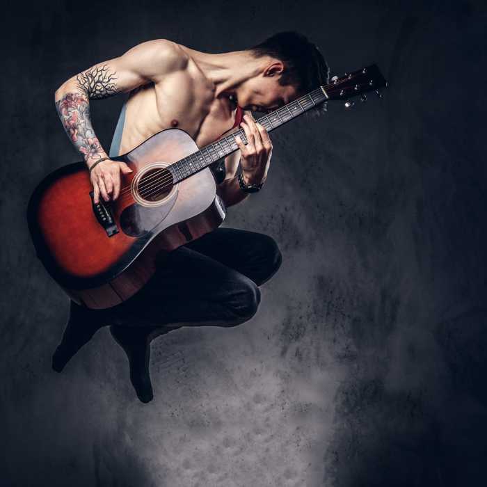músico com visual incrível, tatuado, com violão